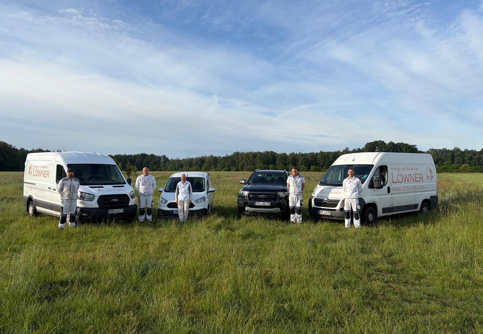 Mathias Löwner mit seinem Team vor den Firmenfahrzeugen