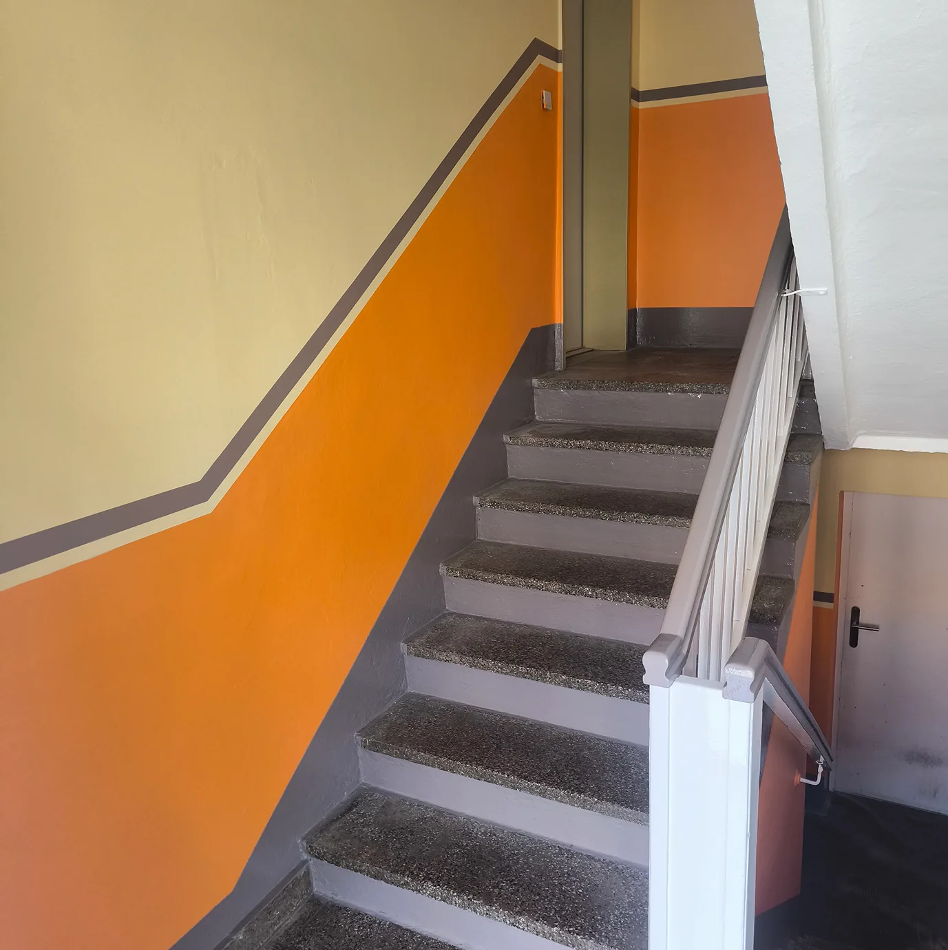 Treppenhaus nach der Sanierung mit orangem Anstrich