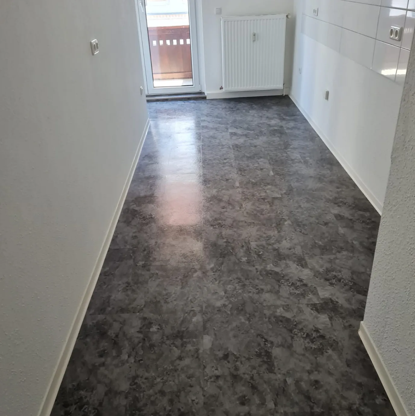 Neu verlegter grauer Bodenbelag in einem leeren Raum