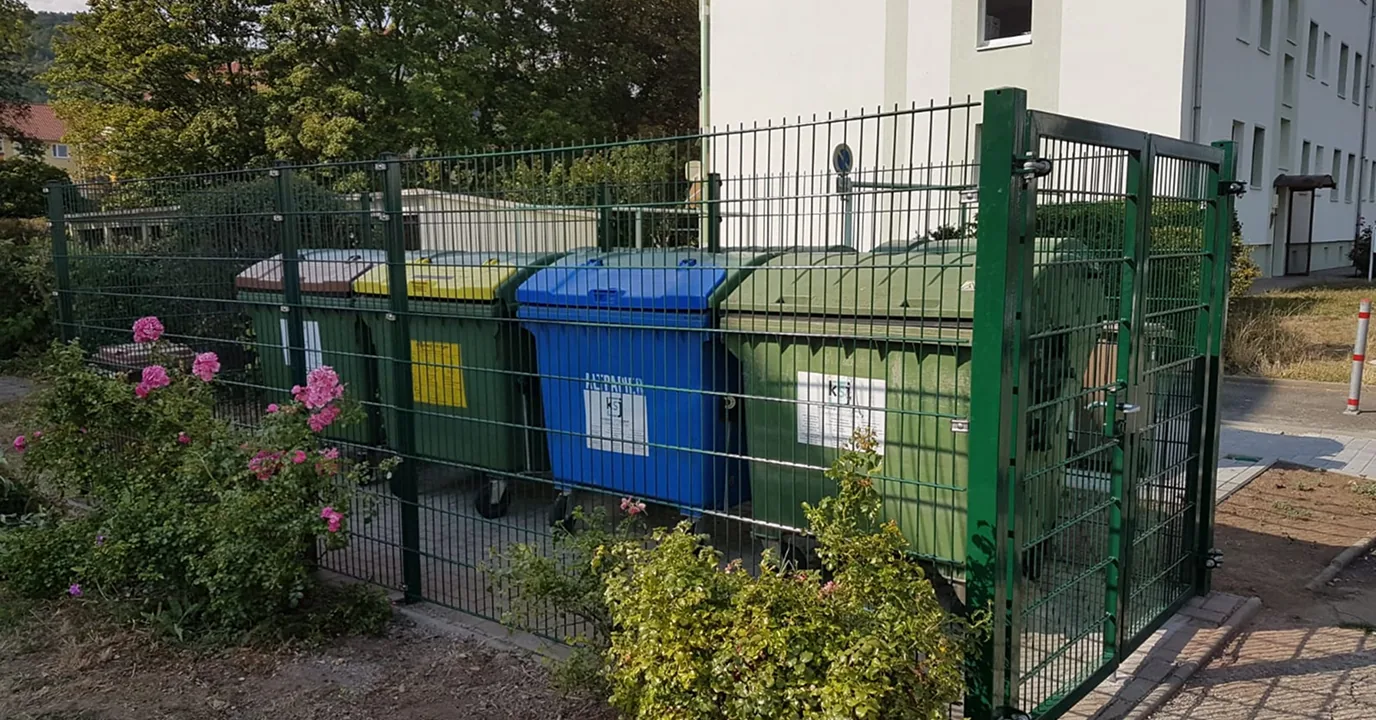 Grüner Gittermattenzaun als Sichtschutz vor Mülltonnen