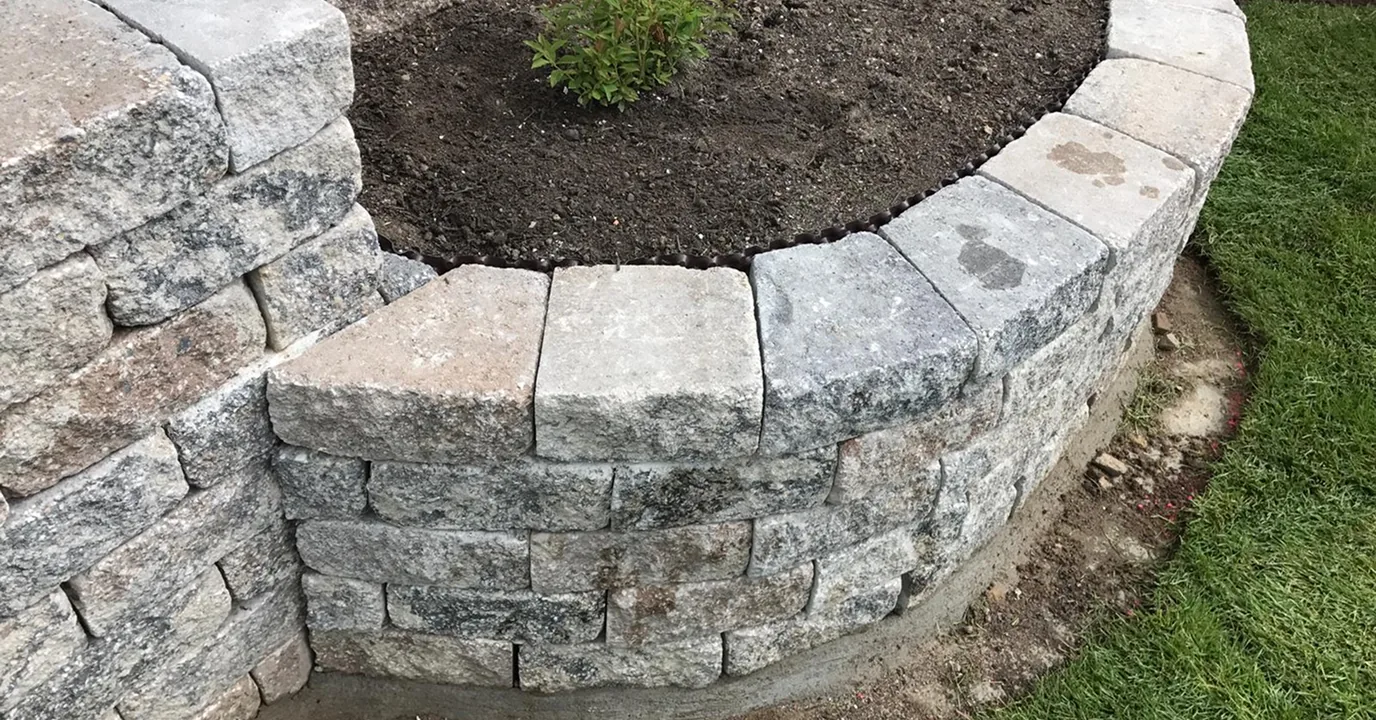 Trockenmauer aus Naturstein mit bepflanztem Beet